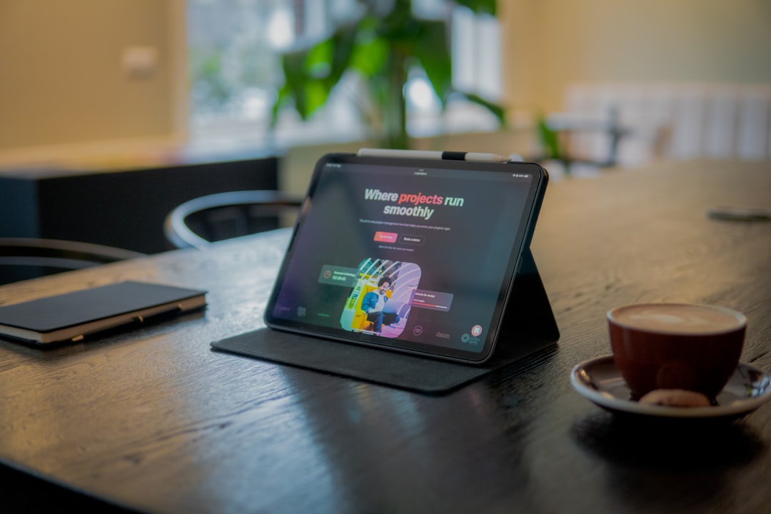 a tablet sitting on top of a wooden table next to a cup of coffee