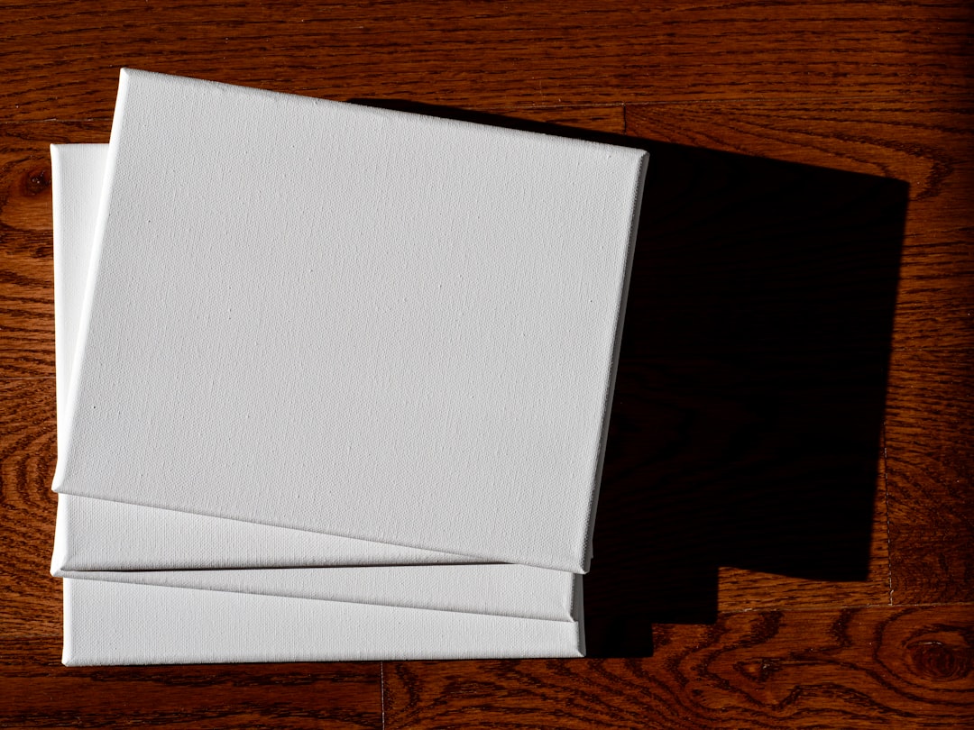 Three blank canvases stacked on a wooden surface